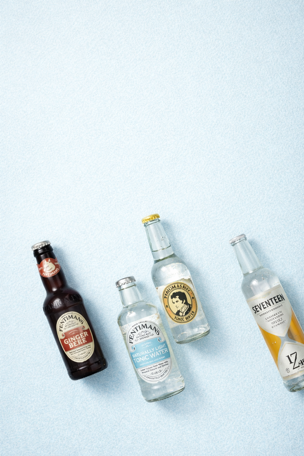 Tonic- und Fillerflaschen auf hellem, eisblauem Hintergrund.